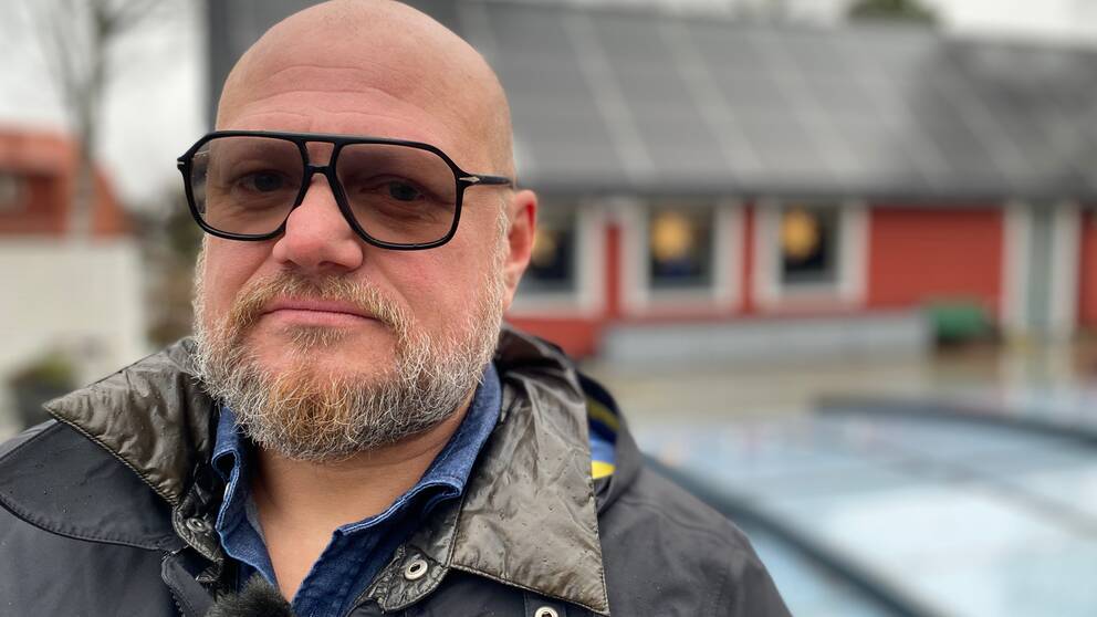 Porträttbild på Mikael Magnusson. En Eskilstunabo som är besviken på att han solcellsanläggning inte håller för det han anser att företaget lovat. I bakgrunden skymtar ett rött hus med en solcellsplanel på taket.
