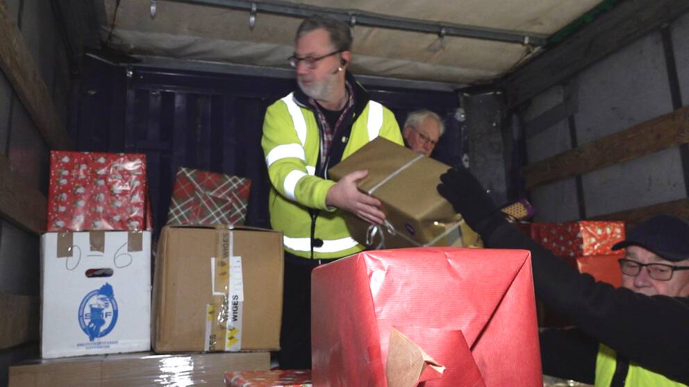 Tre äldre män från Sam-hjälp packar in julklappar i en lastbil.