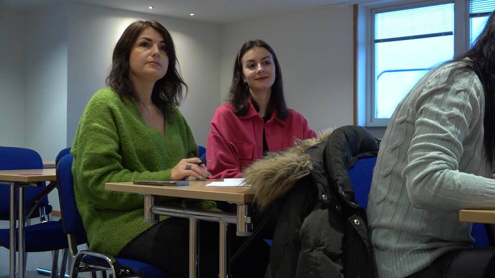 Bild på två kvinnor, en i grön tröja och en i rosa tröja. De sitter vid ett bord. Kvinnorna heter Tetiana Ivanova från Dnipro och Asiiat Dorokova från Kharkiv. De har varit i Sverige i sju månader och lär sig nu svenska i Borås.