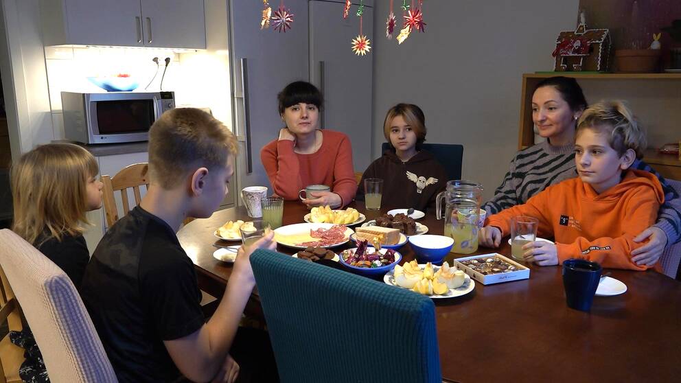Tre ukrainska mammor och deras barn sitter runt ett matbord dukat med godsaker i sitt hem i Dalarna, där de kommer fira nyår efter att de flytt kriget i Ukraina.