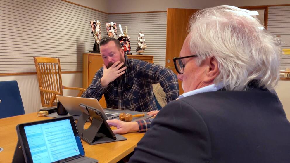 Bild på två män som sitter vid datorer vid ett bord. Mannen närmast bil d har kostym och vitt hår, sitter med ryggen mot kameran. Mannen på andra sidan bordet har skjorta och heter Martin Pettersson. Han är från SD och styr i Uddevalla.