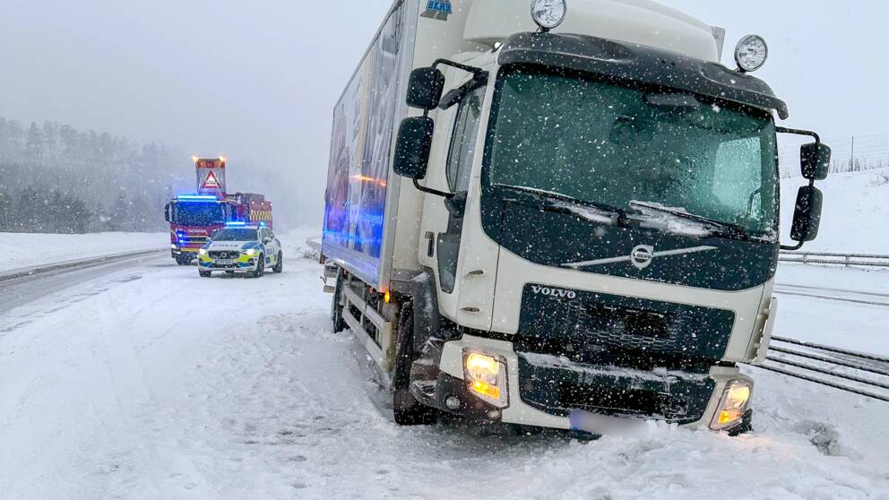 En lastbil i snön, står lite lutad mot mitträcket på E6