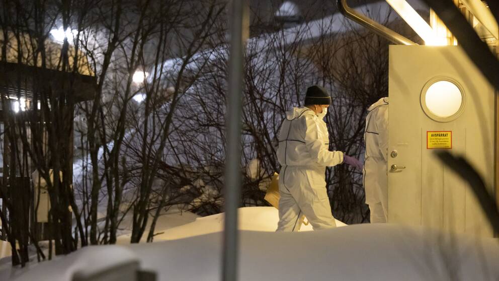Bilden visar när personer iklädda vita skyddskläder och munskydd går in i ett hus med skylten ”Avspärrat” på dörren, i samband med mordet på 8-åriga Tintin i Luleå.