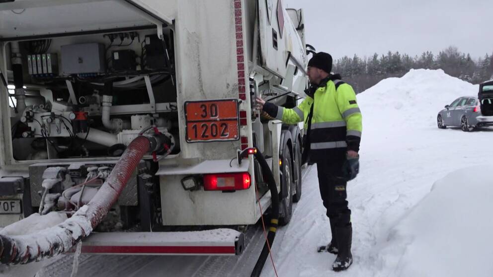 Lastbilsföraren Mattias Björklund i Skellefteå står bredvid en tankbil i Skellefteå. Det är vinter och mycket snö på marken. Bakom honom synd en snöhög och en bil.