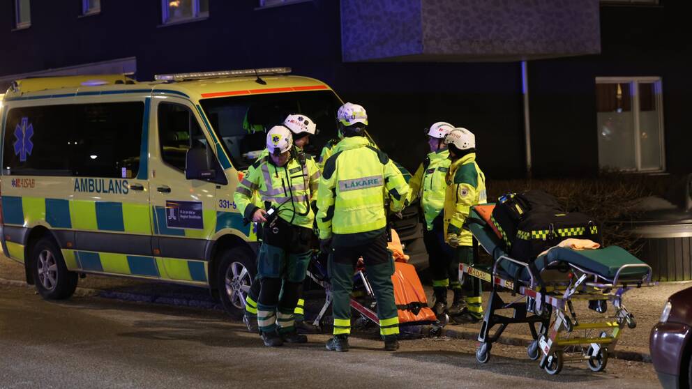 Blåljuspersonal arbetar utomhus i kvällsmörkret efter explosionen i ett trapphus i Årsta i södra Stockholm. 