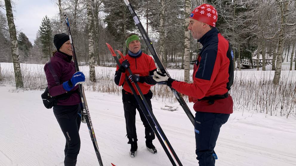 Två skidåkare, en man och en kvinna, får instruktioner av en skidinstruktör i skidspåren