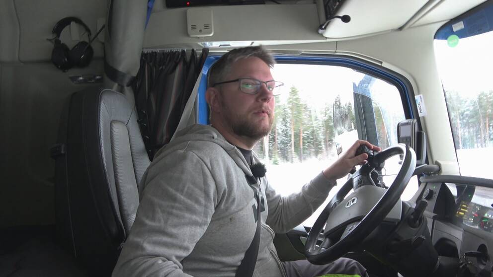 Lastbilschauffören Andreas Nyqvist sitter i sin hytt. Han har ljust hår, skägg och glasögon. Vänster hand är placerad på ratten och blicken är fäst åt höger. Det är ljust ute och i bakgrunden syns barrskog.