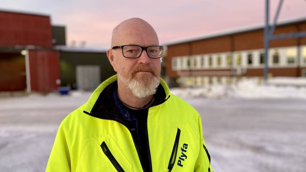 Svarvaren Mikael Nordström står utanför fabriken Plyfa med reflexjacka i soluppgången.