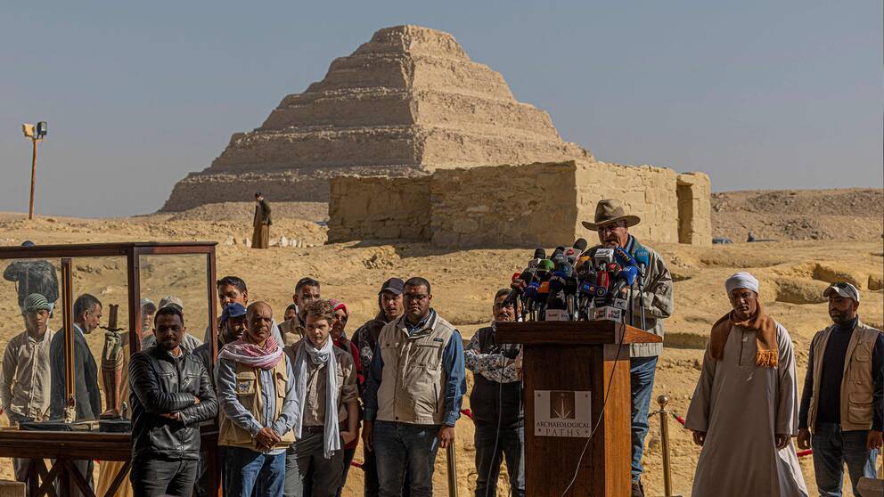 Presskonferens i öknen och i bakgrunden syns en pyramid.