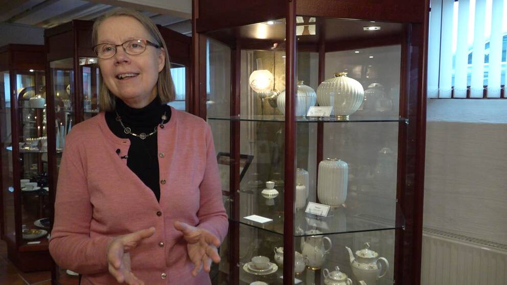 Museiintendenten Christina Öberg på Porslinsmuseet i Karlskrona står framför en hylla med vitt porslin.