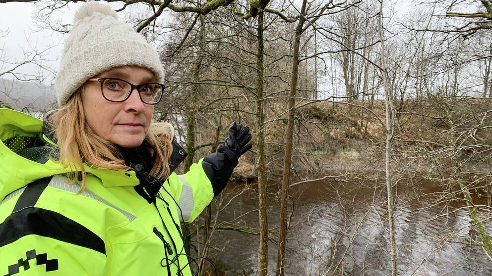 Karin Odén är geotekniker på SGI, Statens geotekniska institut står vid vattnet och visar hur lera rasat ner i Göta älv nära Lilla Edet.