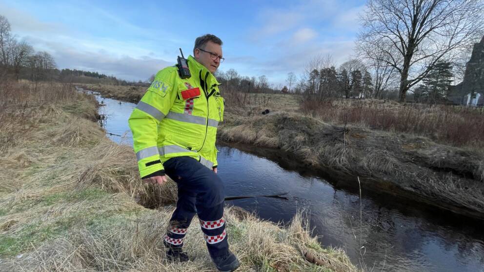 Micael Holmstrand från räddningstjänsten i Ljungby visar hur fåran vid ån Lagan i Hamneda ska byggas.