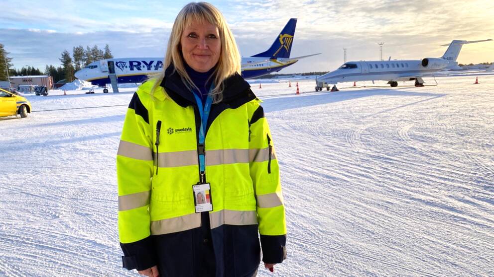 Ann-Christin Viklund poserar nere på flygdäcket framför två olika plan hemmahörande på Luleå airport. 