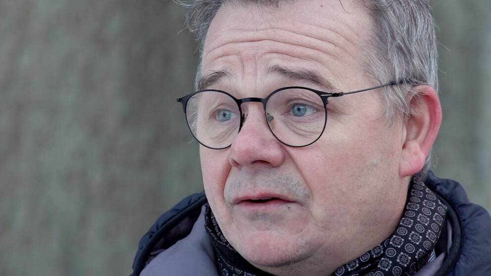 Porträtt av en man med tunnbågade runda glasögon.