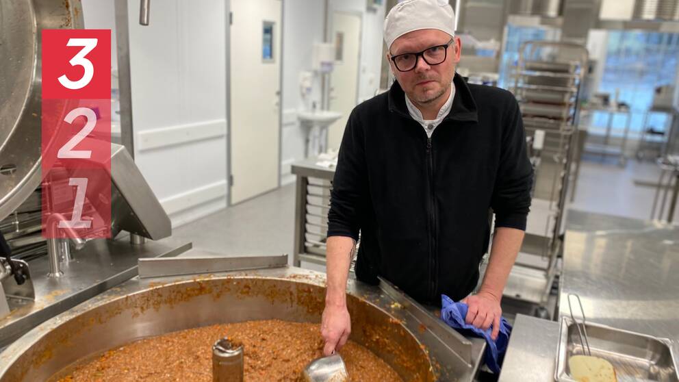Bild på en man i 50-årsålden med kockmössa och svarta glasögon. Han står framför en stor gryta med köttfärssås som han rör om i. I bakgrunden skymtar ett storkök.