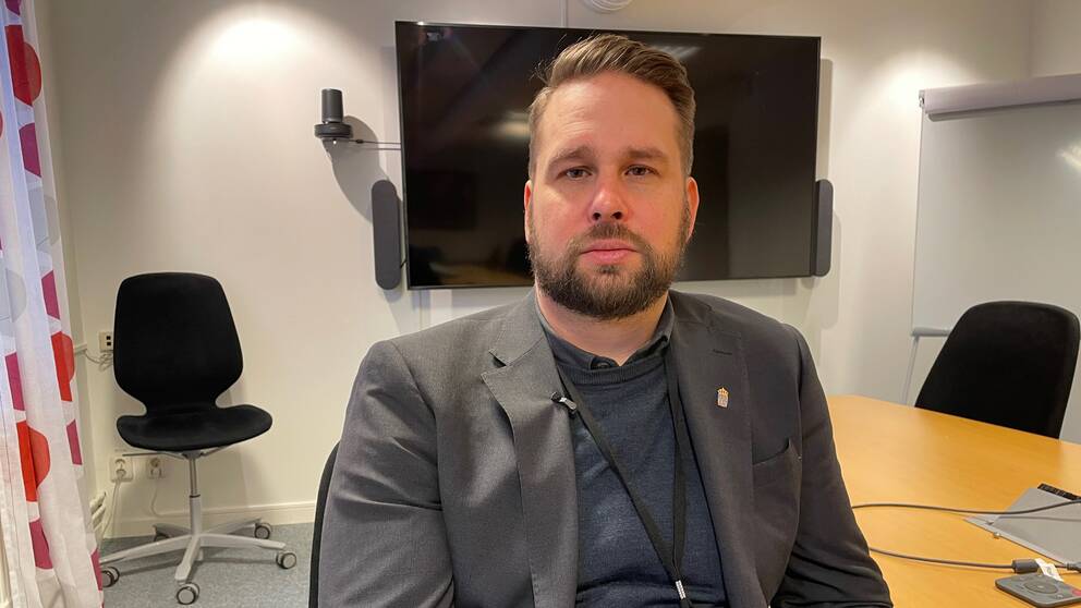 David Ström sitter i ett mötesrum framför en tv. Omkring sig har han ett par stolar.