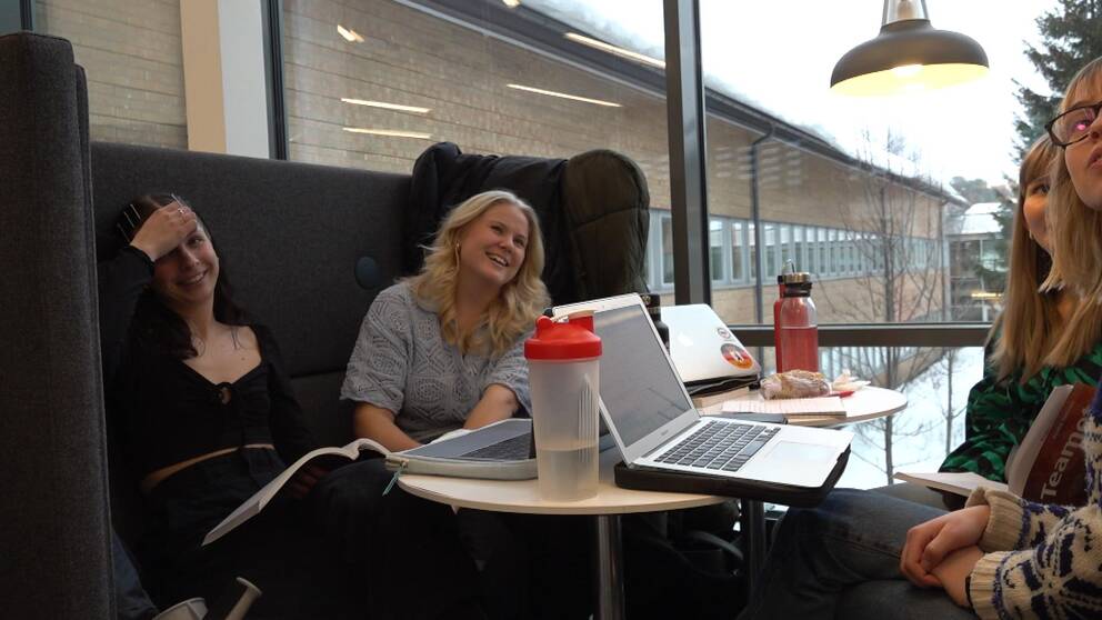 Fyra kvinnor sitter runt ett bord som är belamrat av datorer och vattenflaskor. Två av dem skrattar.