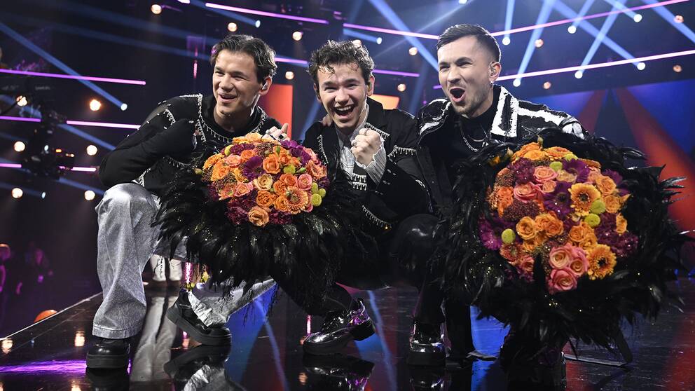Marcus och Martinus och Paul Rey hållandes blommor på scen efter besked att de gått vidare i melodifestivalen.