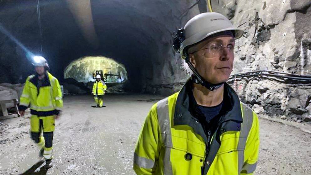 Tre personer är inne i en tunnel under korsvägen. De har gula varselkläder på sig och skyddshjälmar