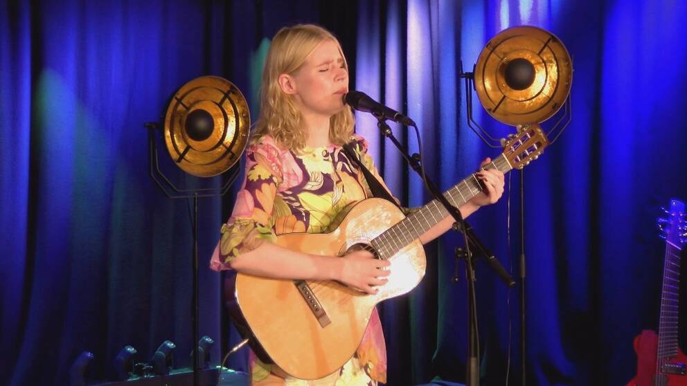 På bilden syns en kvinna som sjunger och spelar gitarr. Hon heter Hildur Höglind.