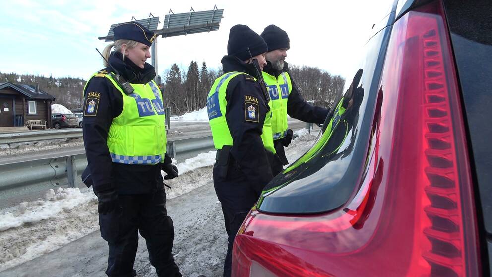 Tre personer i tullens uniform och reflexväst pratar med en bilförare vid tullstationen i Storlien, vintertid