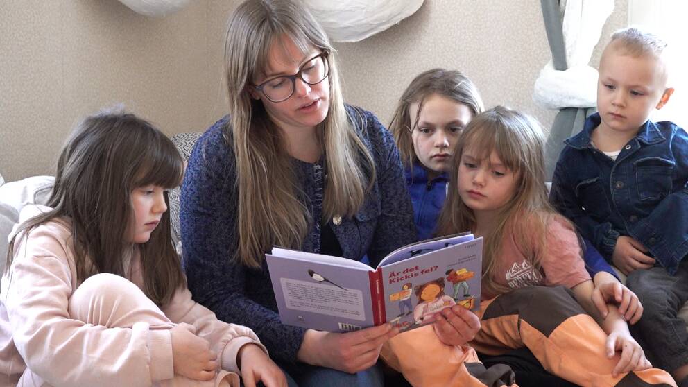 Författaren Sofia Sköld läser sin bok med titeln Är det Kickis fel? för barn som sitter runt henne i en soffa.