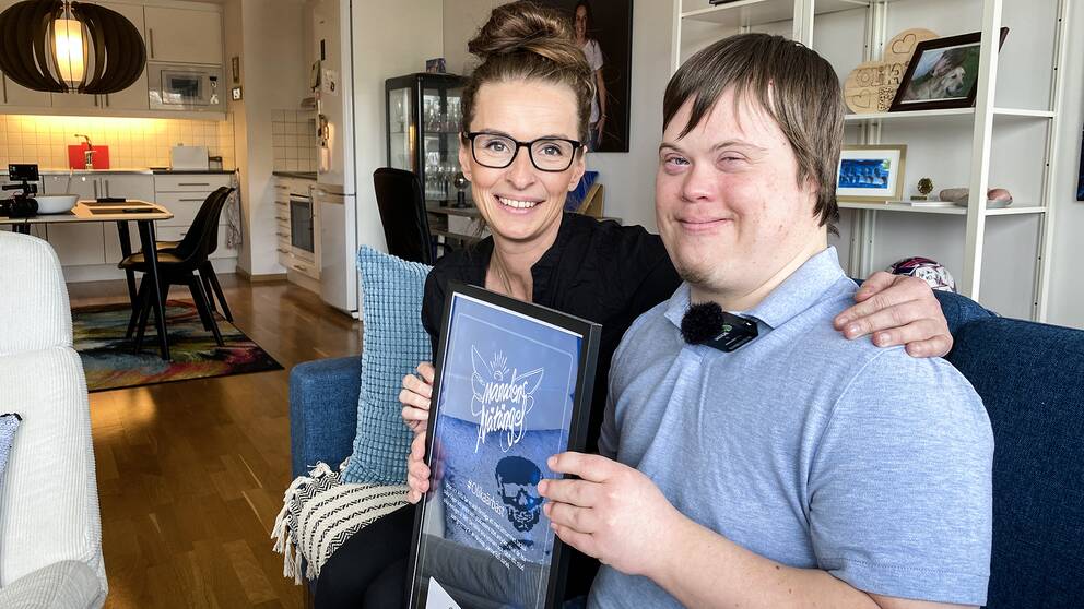 Jonas Wiman och Anna Ginsthammar med priset som de fått för podden #Olikaärbäst, hemma i Jonas lägenhet.