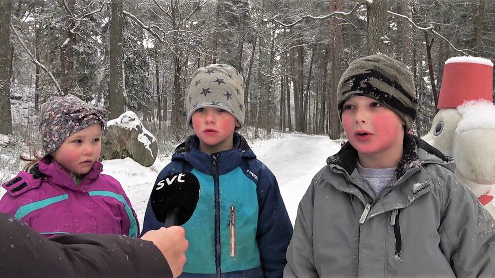 Ida, Nilss och Elias, tre förskolebarn, står ute i snön med en skulptur bakom sig och blir intervjuade av SVT. 