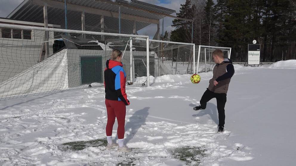 På bilden står Greta Söderberg och Linus Karlgren från fotbollsgymnasiet i Ljusdal och leker med en boll. De står på platsen där fotbollstältet stod förut, på Älvvallen.