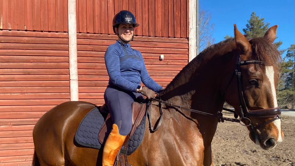 Kvinna som rider på häst i solskenet