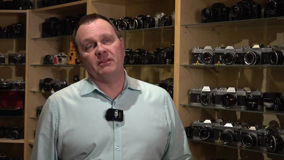 Cyberphotos vd Patrik Olsson intervjuas framför hyllor med kameror.