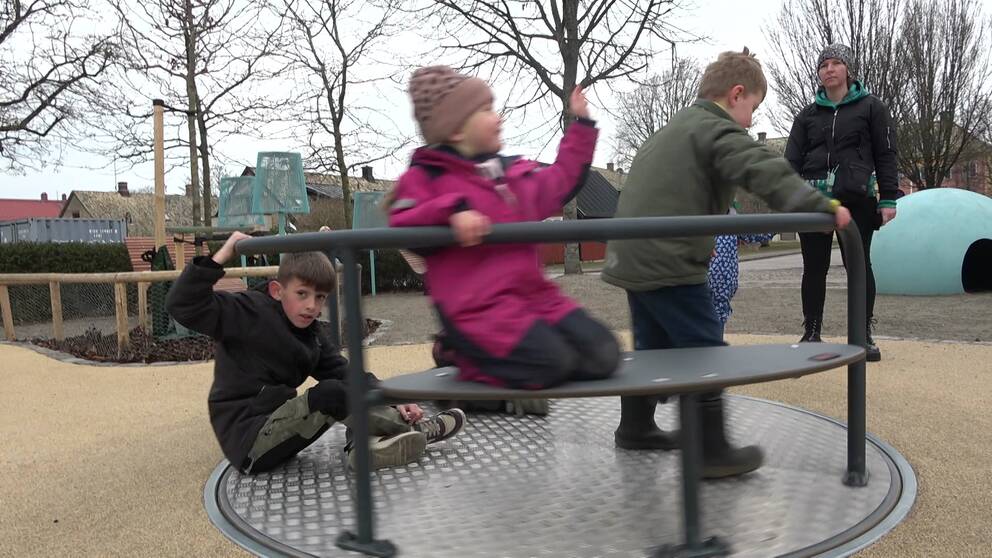 Barn som sitter på en karusell på en lekplats.