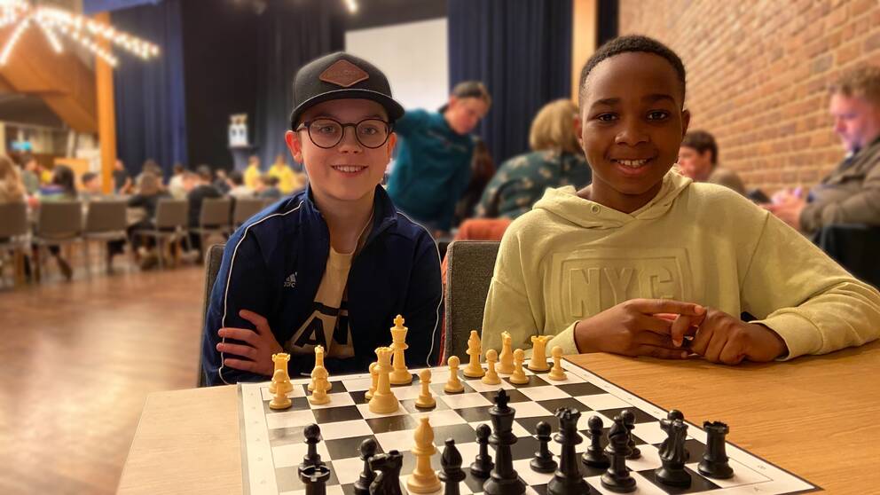 Två unga pojkar som sitter vid ett schackbräde.
