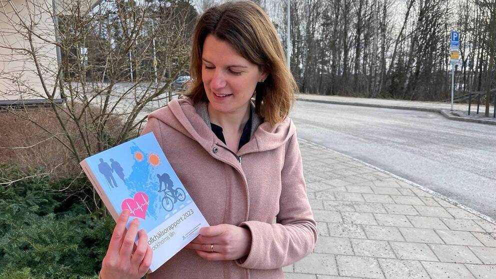 Redaktör för folkhälsorapporten 2023 i Region Stockholm visar upp rapporten