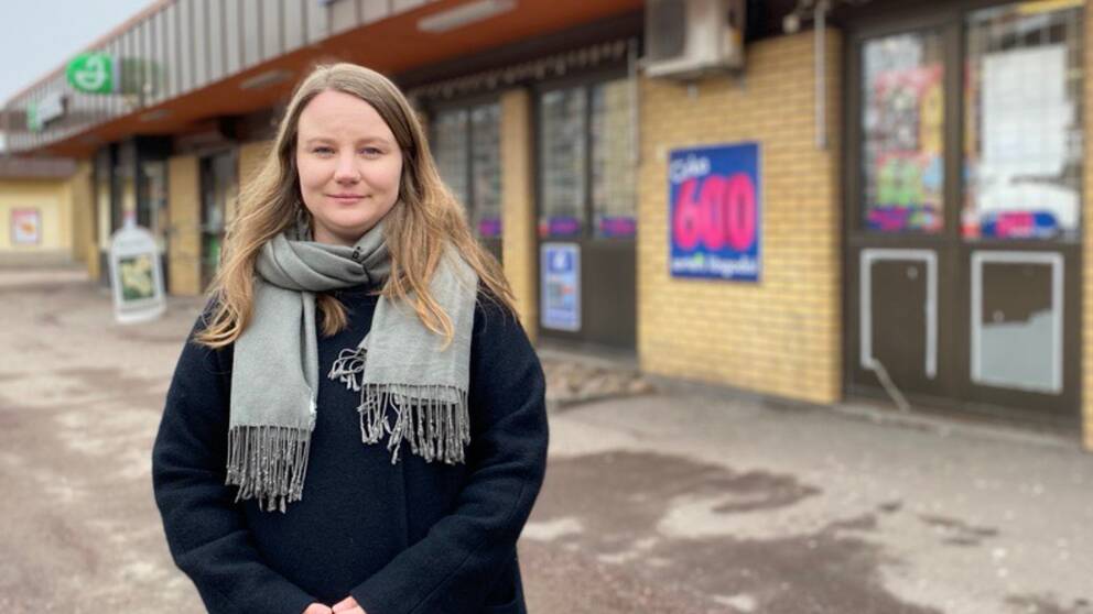 Stadsarkitekten Isabella Netz står vid ett lågt gult tegelhus som inhyser affärsverksamheter.