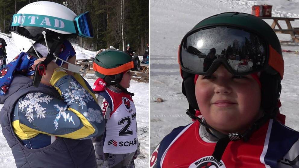 Två barn i skidhjälmar står i en skidbacke.