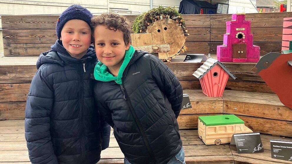 Jack Szabo Lindstrand och Tage Järte står framför ett antal färgglada fågelholkar som skolbarn gjort. 