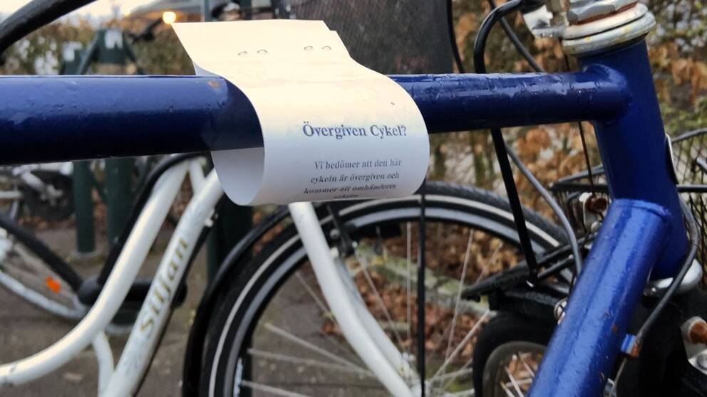 En cykel med en lapp runt ramen. På lappen har Gatukontoret i Falkenberg skrivit att cykeln bedöms vara övergiven och att den kan komma att forslas bort.