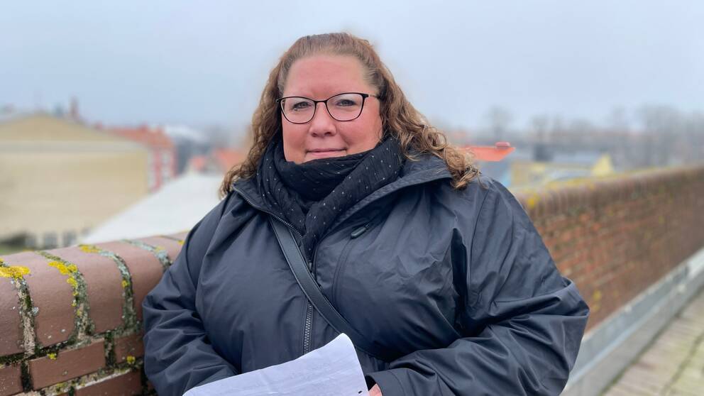 Feriesamordnare på Karlskrona kommun står lutad mot en vägg med en lista över sommarjobb i händerna.