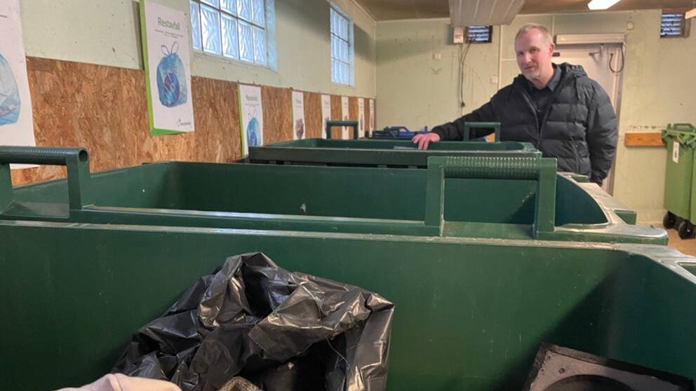 Per Gunnarsson, it- och digitaliseringsansvarig på SSAM, Södra Smålands avfall och miljö, står i ett soprum och håller i en grön soptunna.