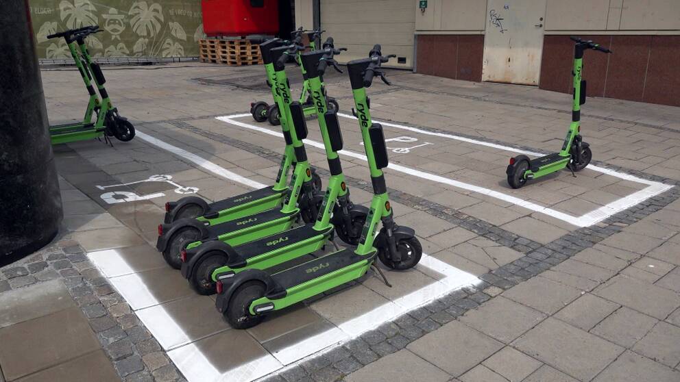 Flera elsparkcyklar står parkerade på speciella parkeringsplatser för elsparkcyklar.