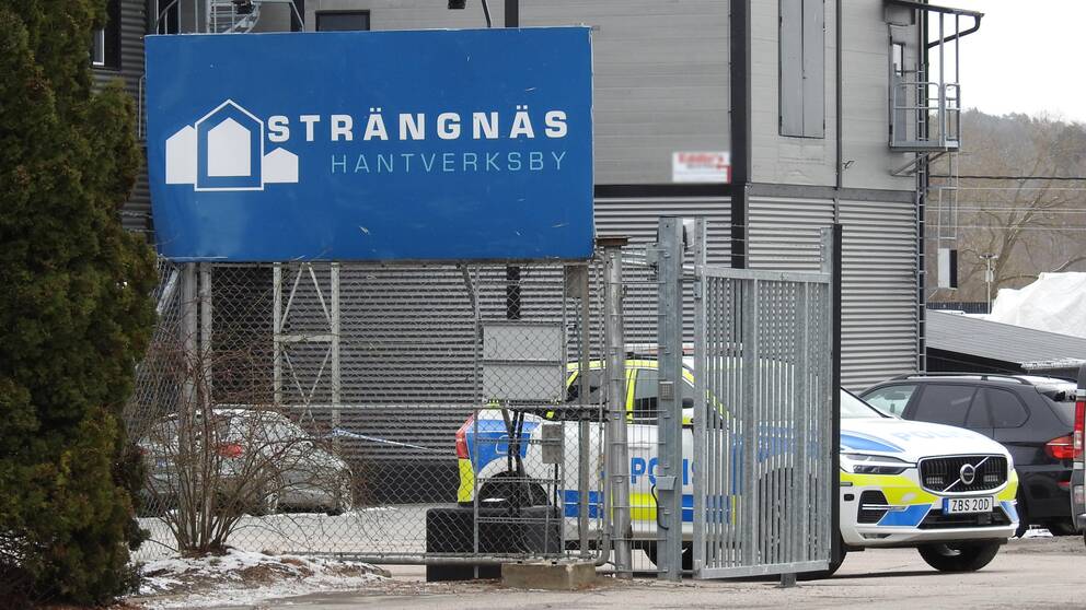 Bild tagen utanför Strängnäs Hantverksby. Man ser ser en skylt med deras logotyp och en polisbil som står bakom grindarna.
