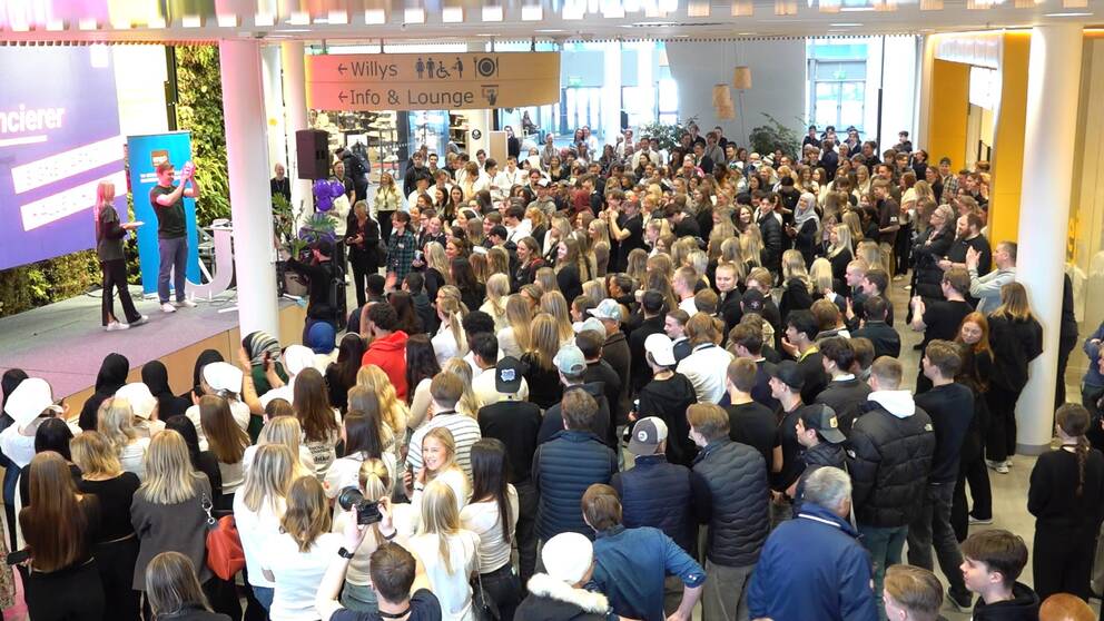 En stor folksamling bestående av ungdomar som besöker UF-mässan i Umeå tittar på när två ungdomar på scen berättar om sin företagsidé.