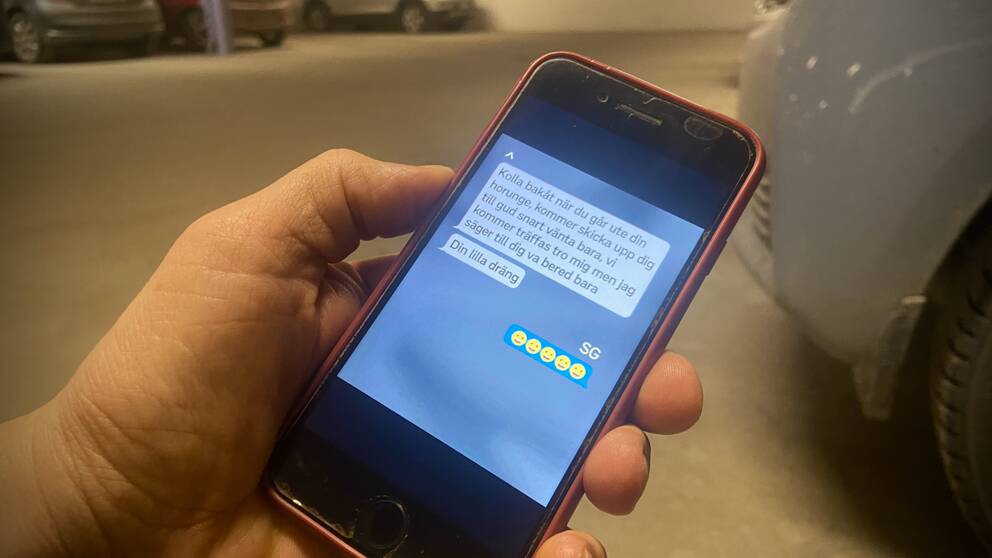 En hand håller i en mobiltelefon med en chattkonversation.