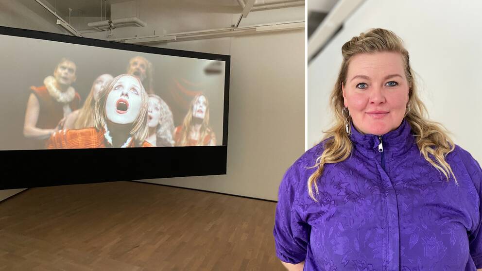 Em kvinna som står framför en stor skärm i en konsthall