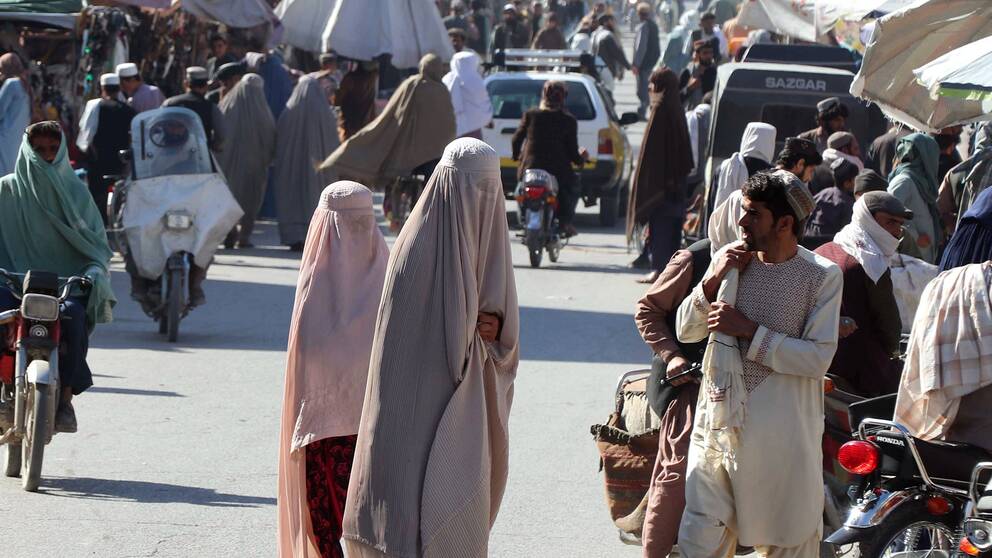 Två kvinnor i ett folkhav i Afghanistan.