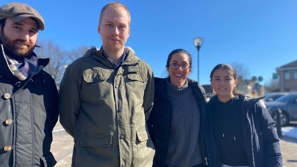 Fyra personer står utomhus och tittar in mot kameran.