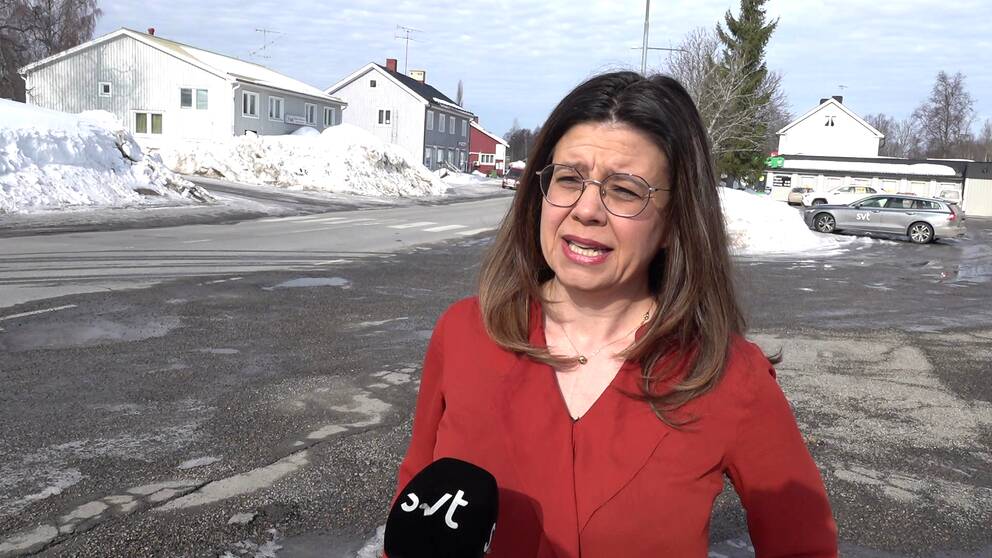 Rksdagspolitikern Helena Lindahl (C) har axellångt brunt hår, glasögon och står iklädd en röd tröja på en gårdsplan i ett bostadsområde när hon framför sin kritik mot regeringen gällande skattesmällen som drabbar biogasproducenter.