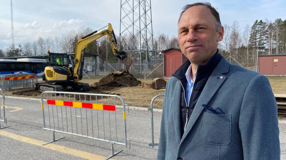 En man står framför en grävskopa.