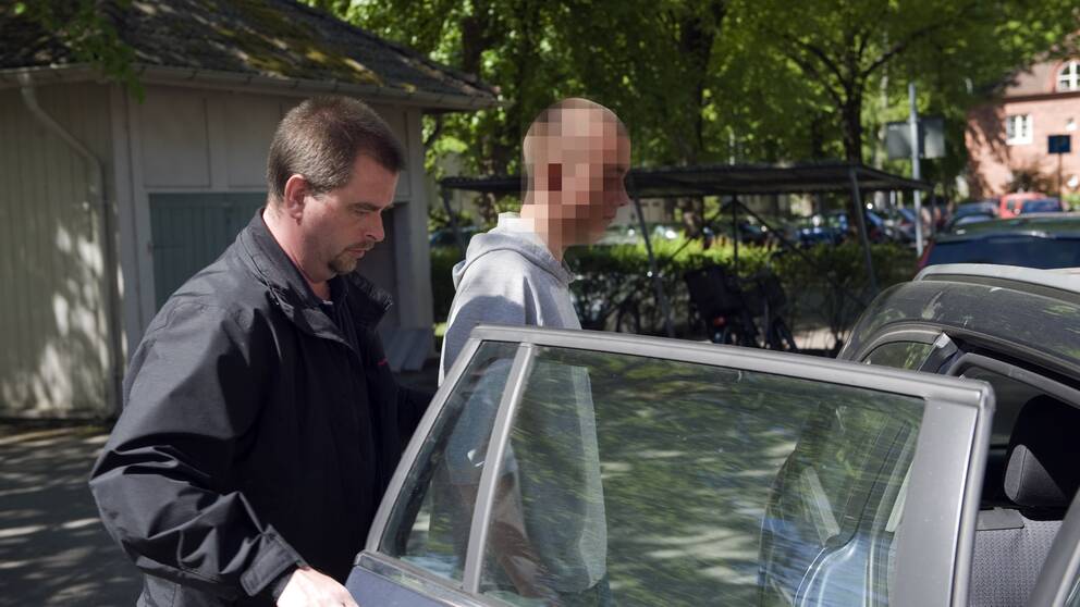 Man, misstänkt för mord, på väg in i bil.